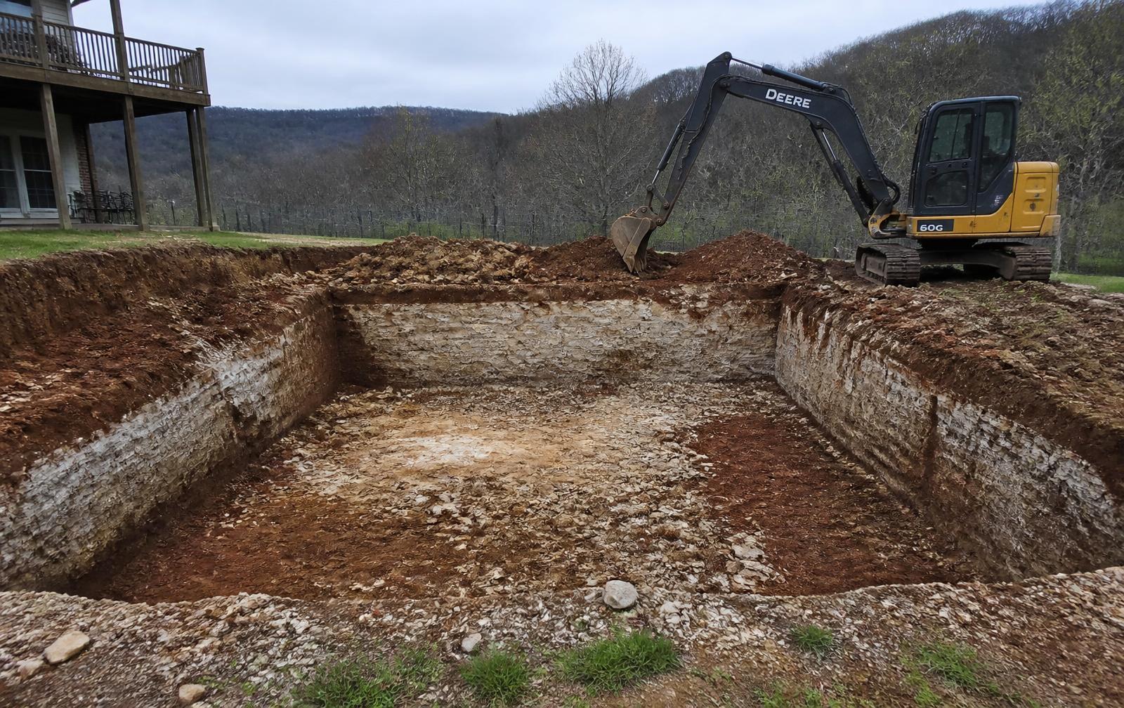 Excavator digging an inground pool hole into limestone and clay in a Chattanooga, TN backyard